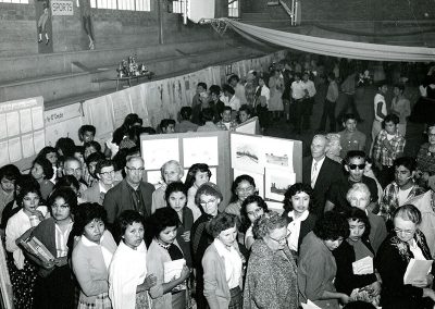 1950 black and white photo of a crowded room with art on panel boards and people looking at it