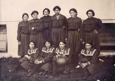 1904 black and white team photo of young Native women basketball players in black sailor style pinafores